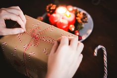 a person holding a wrapped present in front of a plate with candy canes on it