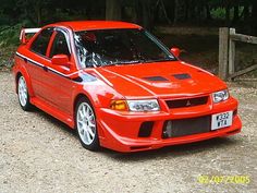 an orange car parked in front of a wooden fence