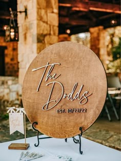 a wooden sign sitting on top of a table next to a white cloth covered table