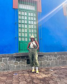 a woman standing in front of a blue and green building with her hands on her hips