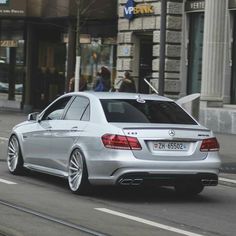 a silver car driving down a street next to tall buildings