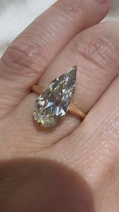 a woman's hand with a ring on it and a pear shaped diamond in the middle