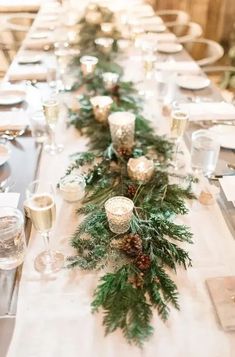 a long table with candles and greenery is set for an elegant christmas dinner party