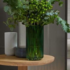 a green vase sitting on top of a wooden table