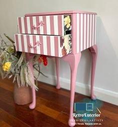 a pink and white striped dresser next to a potted plant on the wooden floor