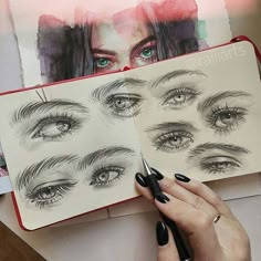 a woman's hand holding a pen over a drawing book with drawings of eyes