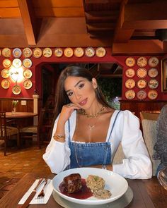 a woman sitting at a table in front of a white plate with food on it