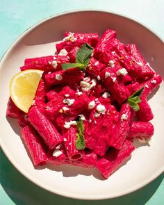 a white plate topped with beets and feta cheese next to a lemon wedge