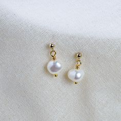 Add a touch of classic elegance to your look with the Aria Earrings. Crafted with a big, lustrous pearl as the centrepiece, these timeless earrings are the perfect choice for any special occasion. The pearl is set in simple yet sophisticated ear studs with a butterfly scroll that will bring out its natural beauty. A stunning addition to your collection. -Free UK and US delivery on all orders -Handmade in England, UK -A-grade freshwater pearls carefully selected for their organic and natural shap Dainty Pearl White 14k Gold Filled Pearl Earrings, Delicate White Pearl Earrings For Everyday, Classic White Pearl Earrings In 14k Gold, Dainty Everyday Pearl Earrings, Minimalist Pearl Earrings With Charm, Classic Pearl Pendant Earrings In 14k Gold Filled, Classic 14k Gold Filled Pearl Pendant Earrings, Classic 14k Gold-filled Pearl Pendant Earrings, Minimalist Pear-shaped Pearl Drop Earrings