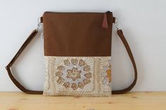 Bolso de lona en color marrón, combinado con tela estampada con motivos de ganchillo. Esta hecho con tela de alta calidad. El asa está hecha con la misma lona, acolchada para darle mayor resistencia, con un regulador para que puedas ajustarla  ala medidas que quieras, tanto cruzado como para llevar en el hombro. No tiene bolsillos, el compartimento principal se cierra con una cremallera que acaba en un tirador de cuero marrón. Forrado con tela acolchada. Muy practico para llevar a diario y muy c Brown Canvas Bag For Daily Use In Fall, Brown Canvas Bag For Fall, Square Beige Shoulder Bag For Fall, Beige Square Shoulder Bag For Fall, Brown Tote Shoulder Bag For Fall, Brown Canvas Shoulder Bag With Adjustable Strap, Brown Bag With Removable Pouch For Fall, Brown Fall Bag With Removable Pouch, Fall Clutch Bag With Adjustable Strap