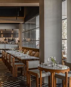 an empty restaurant with checkered flooring and wooden tables set up for two people