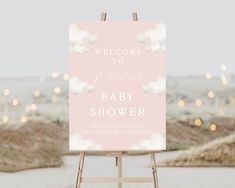 a welcome sign for a baby shower on an easel in front of some lights