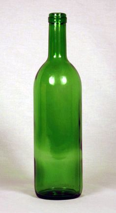 a green glass bottle sitting on top of a white table