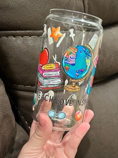 a person holding up a clear glass with some stickers on it