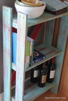 an old wooden shelf with wine bottles and books on it, next to a bowl