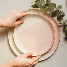 two hands are holding plates on a table