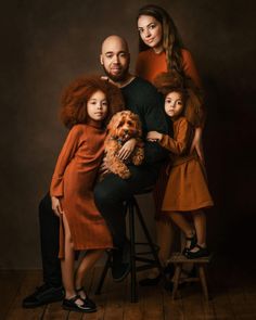 a family poses for a portrait with their dog and two children in front of a dark background