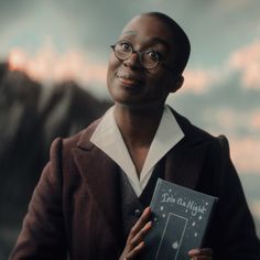 a woman in glasses holding up a book