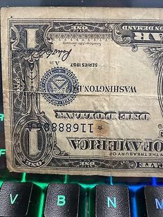 an old one dollar bill sitting on top of a computer keyboard