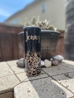 a black and white tumbler sitting on top of a table next to a potted plant