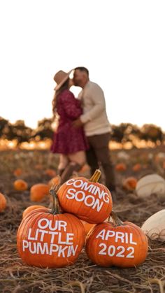 a couple kissing in front of pumpkins with the words coming soon our little pumpkin written on them