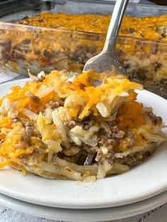 a casserole dish on a white plate with a fork in it and the casserole is ready to be eaten