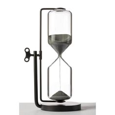 an hourglass with sand in it sitting on a table next to a black stand