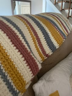 a crocheted blanket sitting on top of a couch next to a stair case