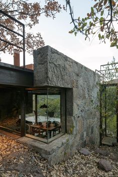 an outdoor dining area in front of a stone building with glass walls and doors on the outside