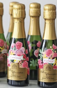 four bottles of champagne with pink flowers on them