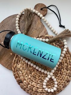 a blue water bottle sitting on top of a wooden board next to a tassel