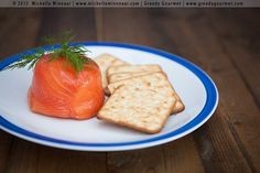 a white plate topped with crackers and a piece of salmon