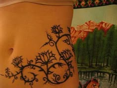 a woman's stomach with an intricate tattoo design on the side of her body