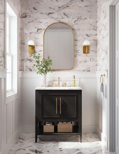 a bathroom with marble walls and flooring has a gold framed mirror above the sink