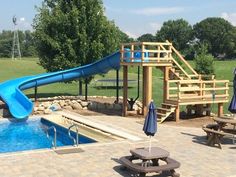 an outdoor pool with a slide and picnic tables