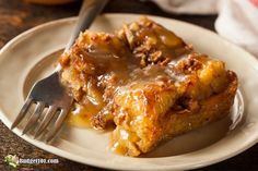 a white plate topped with two pieces of cake covered in caramel sauce next to a fork