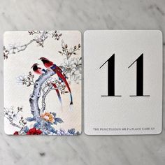 two cards with birds on them sitting next to each other in front of a marble table