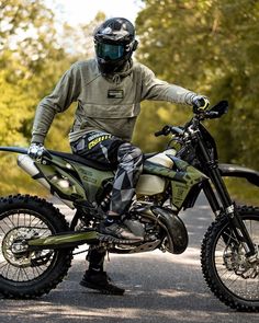 a man is sitting on a dirt bike in the middle of the road wearing a helmet and goggles