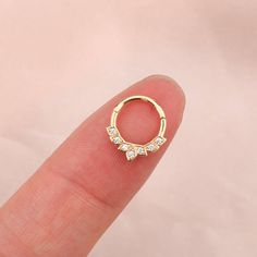 a person's finger with a small gold ring on top of their finger and three smaller white diamonds in the middle