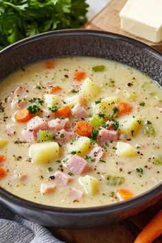 a bowl of ham and potato soup with carrots, parsley on the side