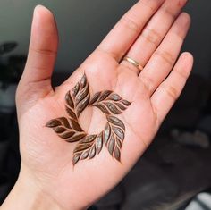 a person's hand with a tattoo on it that is shaped like a leaf