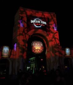 the entrance to universal studios is lit up with red and purple lights for halloween night