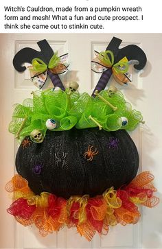 a black pumpkin decorated with green and orange ribbons, spider webs, and googly eyes