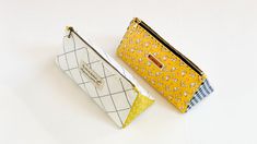 two small purses sitting next to each other on a white surface, one yellow and the other blue