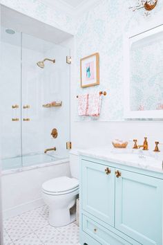 a white toilet sitting next to a walk in shower under a bathroom mirror above a sink