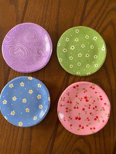 four colorful plates sitting on top of a wooden table