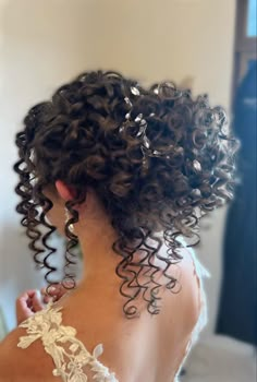 the back of a woman's head, with curly hair and an intricate dress