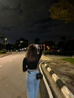 a woman is walking down the street at night