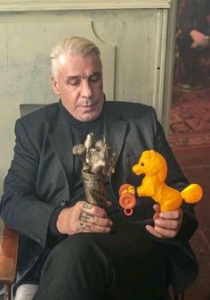 a man sitting in a chair holding a toy horse and an orange rubber ducky