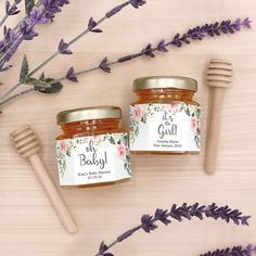 two jars of honey sit next to some lavender flowers